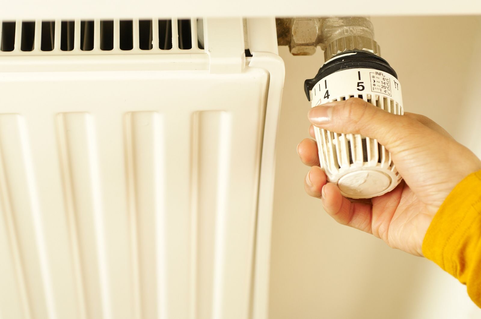 Käsi säätää patterin termostaattia. Lämmityskauden kulutus ratkaisee kuuden kuukauden sähkösopimuksen hinnan.