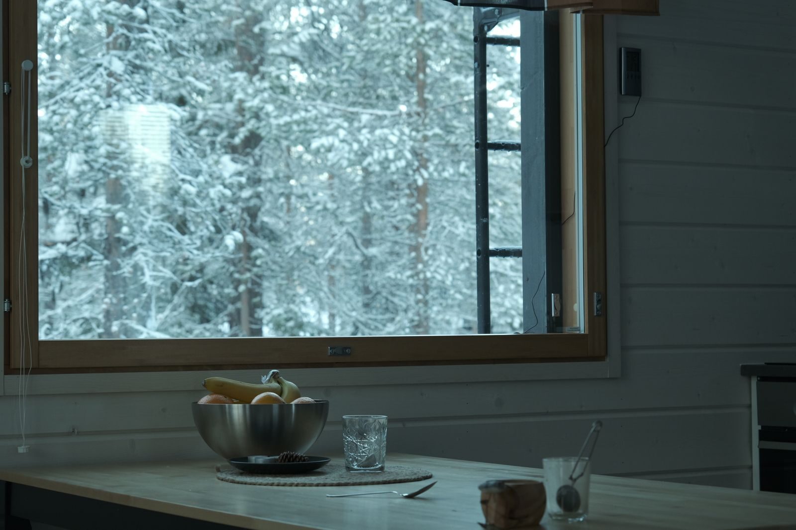 Pöytä ja ikkuna lumiseen metsään. 12 kuukauden sähkösopimus pitää energian hinnan samana yhden talven ja kesän.
