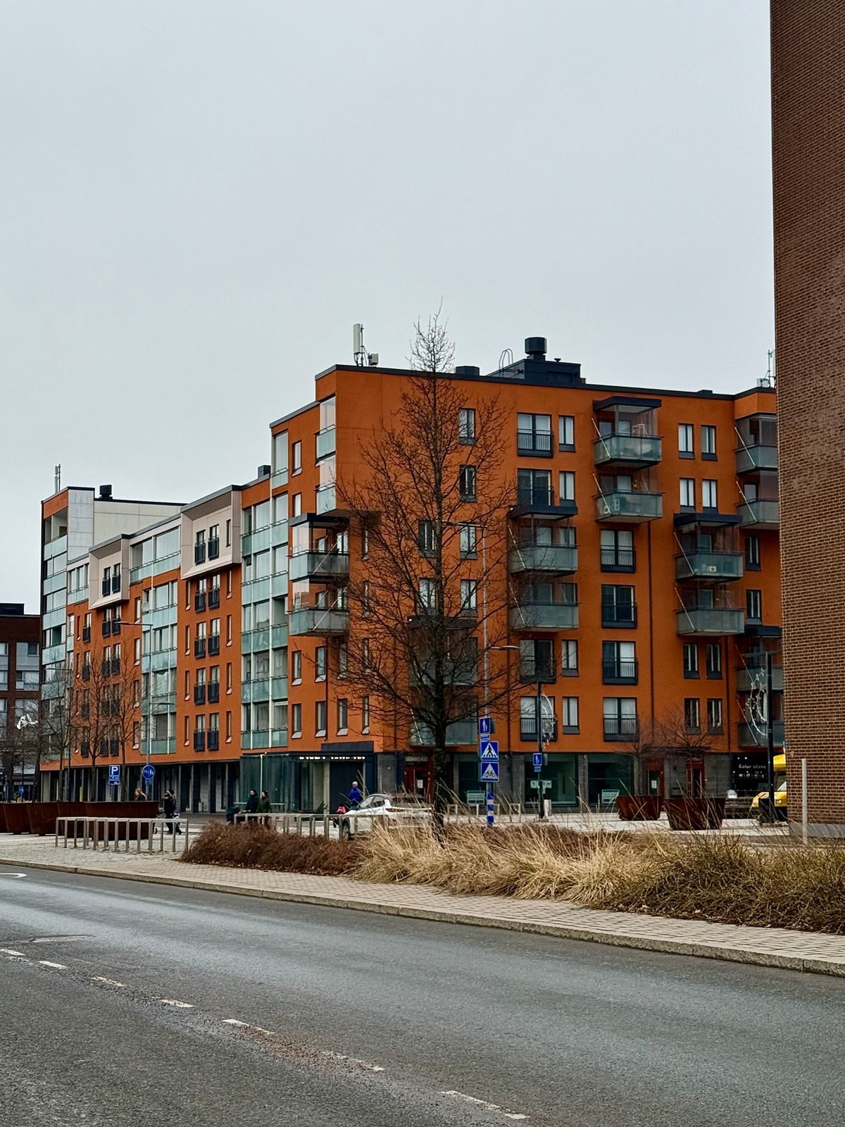 Oranssi kerrostalo Vantaalla harmaan kadun varrella; sähkönmyyjä voi vaihtua ilman, että koti tai mittari vaihtuu.