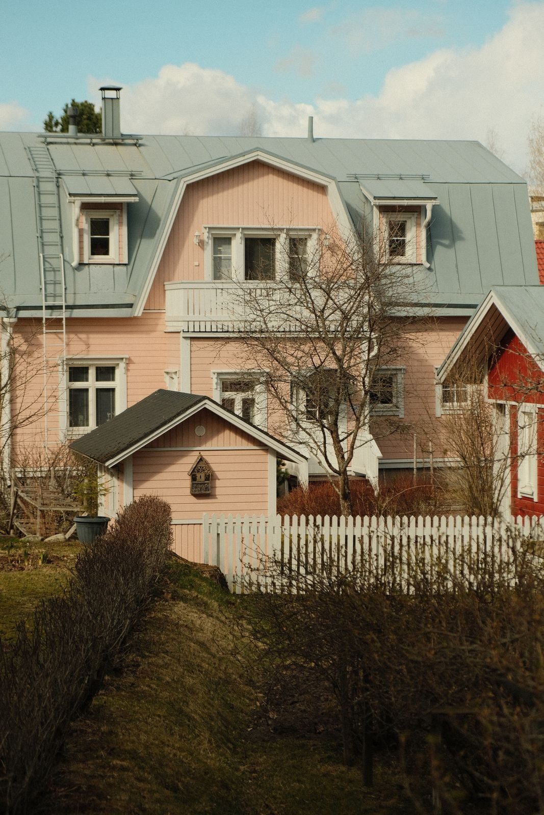 Vaaleanpunainen puutalo ja puutarhapolku