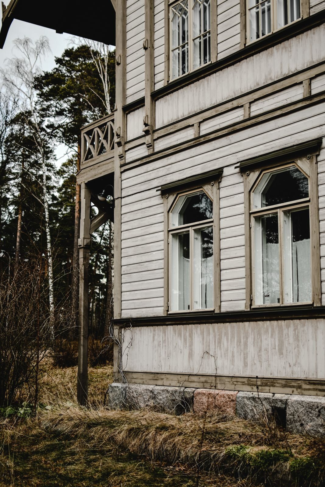 Vaalean puutalon ikkunoita ja syksyinen piha.