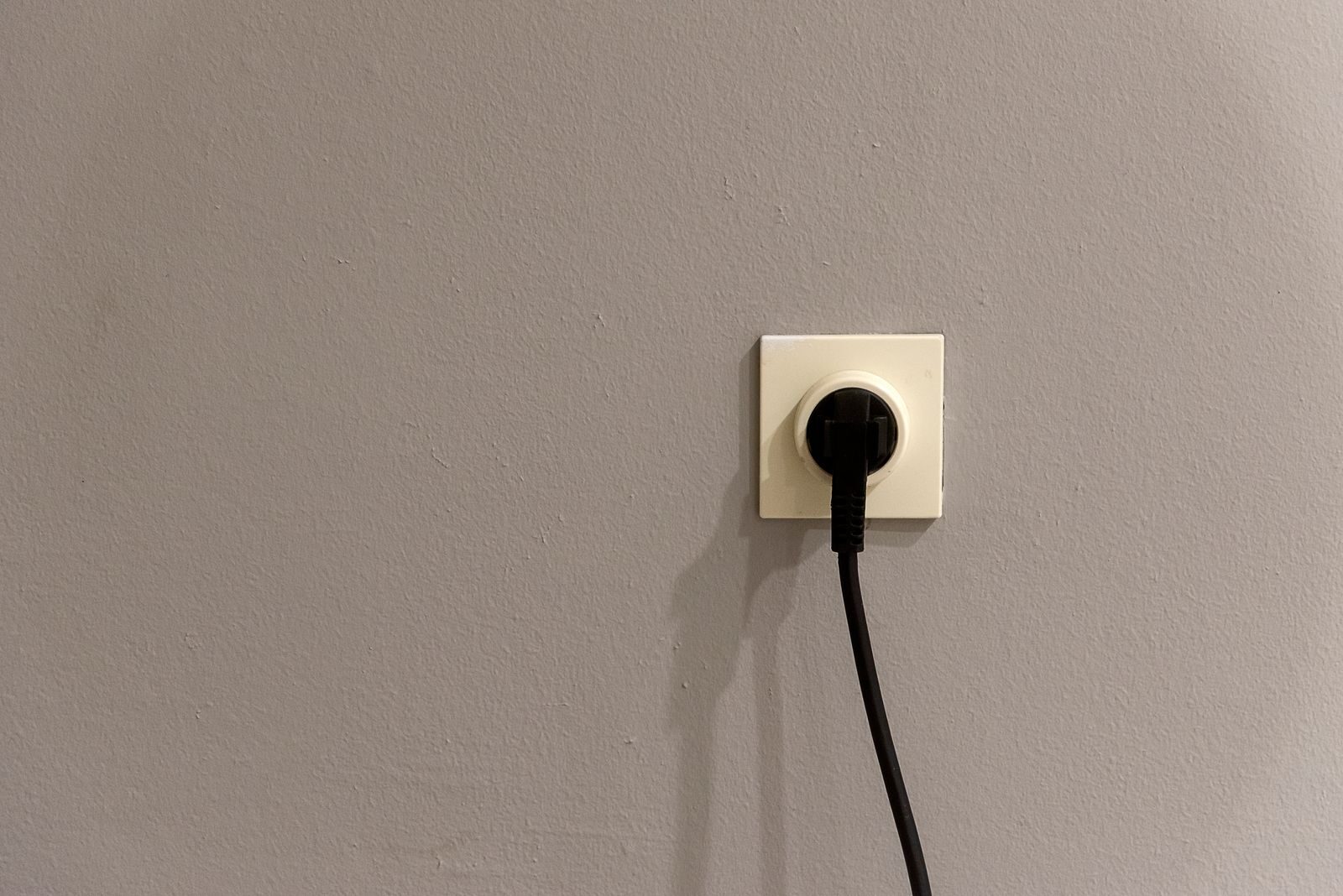 Musta pistotulppa valkoisessa seinäpistorasiassa.