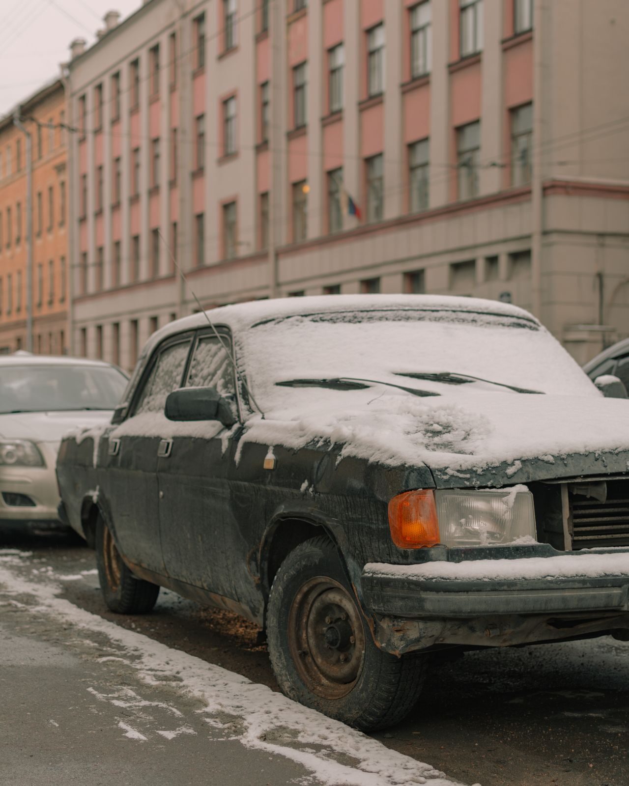 Lumipeitteinen auto pysäköitynä kadun varteen.