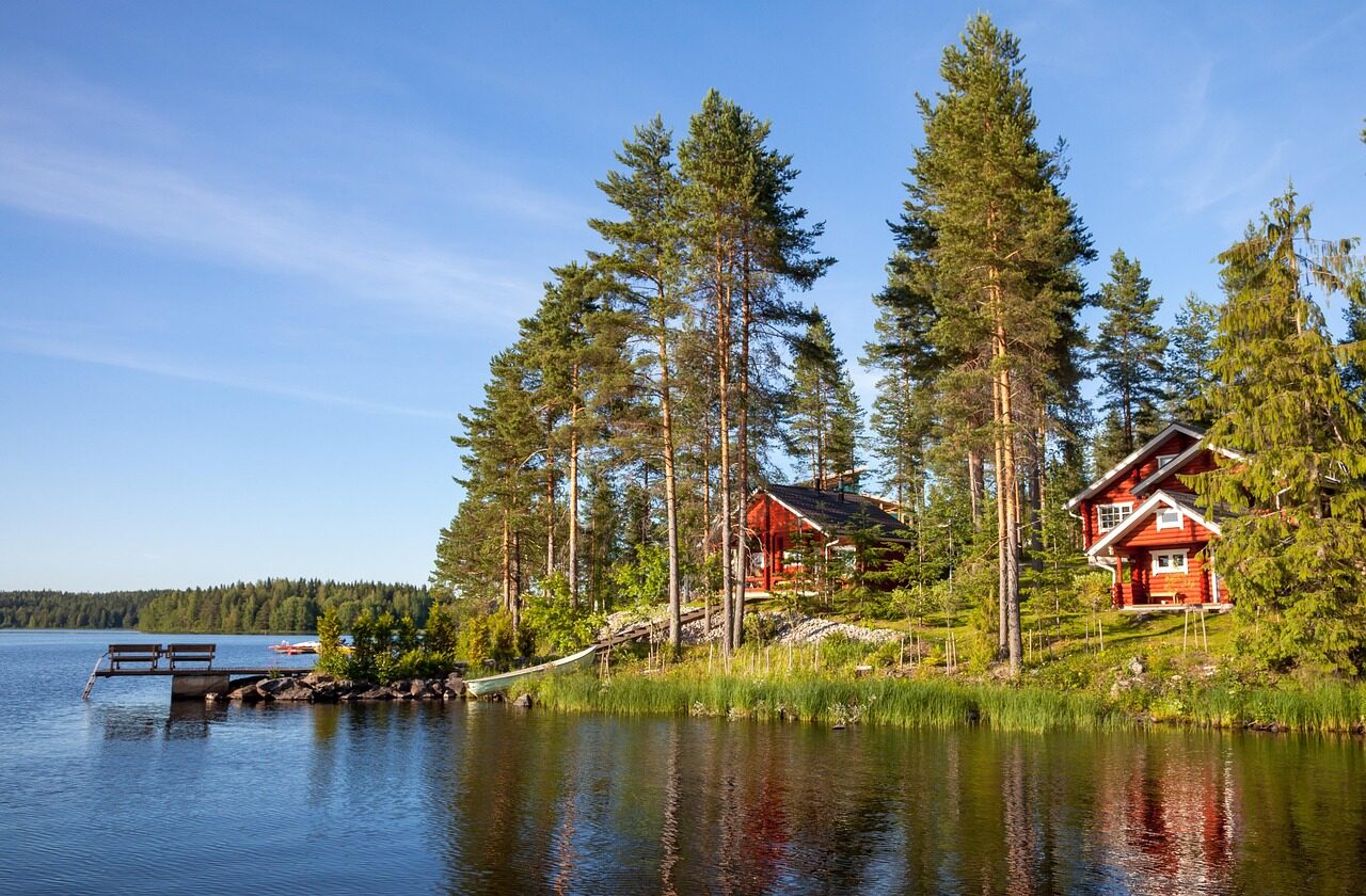Punaisia mökkejä ja laituri metsäisellä järvenrannalla.